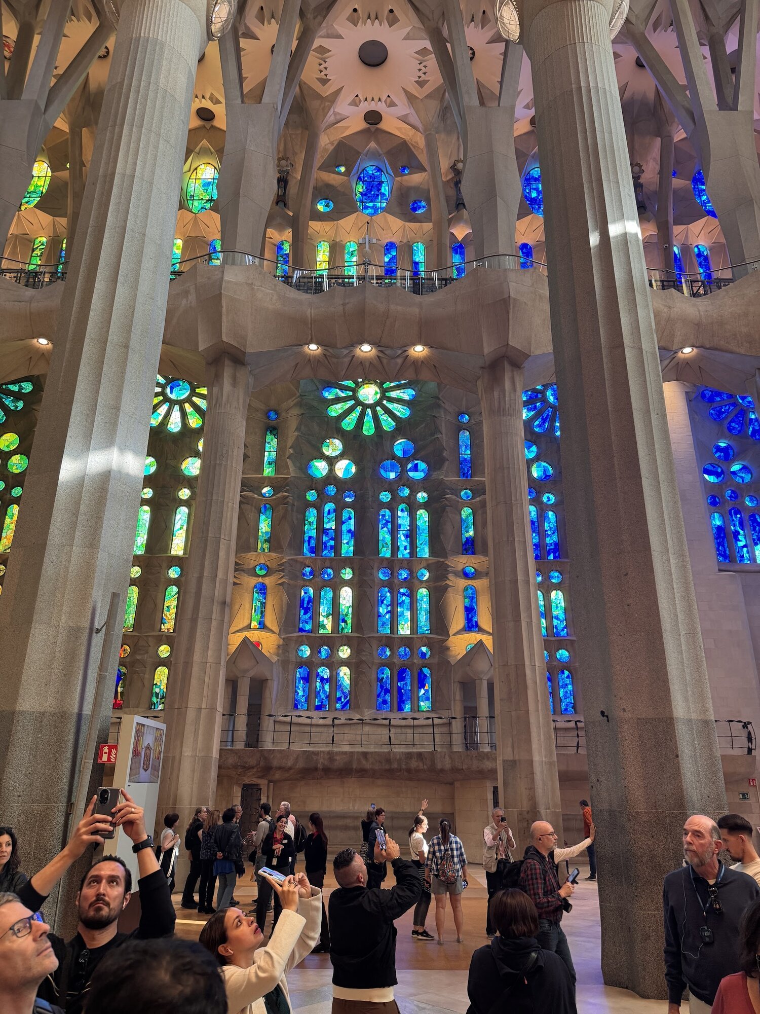 Interior of Sagrada Família with cool blue and green stained glass windows on the west facade
