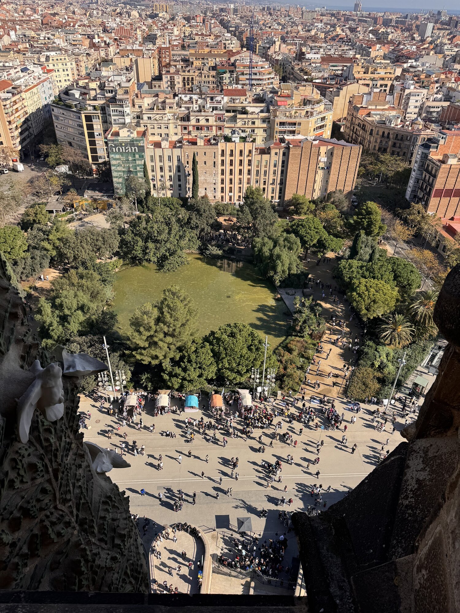 Looking straight down from the Sagrada Família tower over the crowded plaza and Barcelona's Eixample grid stretching to the horizon