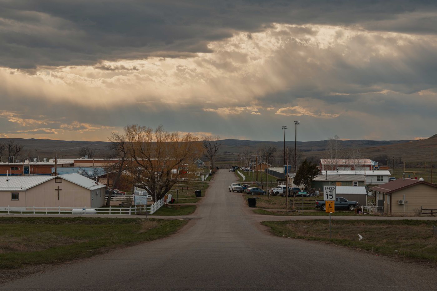 A quiet High Plains main street running straight to the horizon under a dramatic billowing storm sky, church and low buildings lining each side
